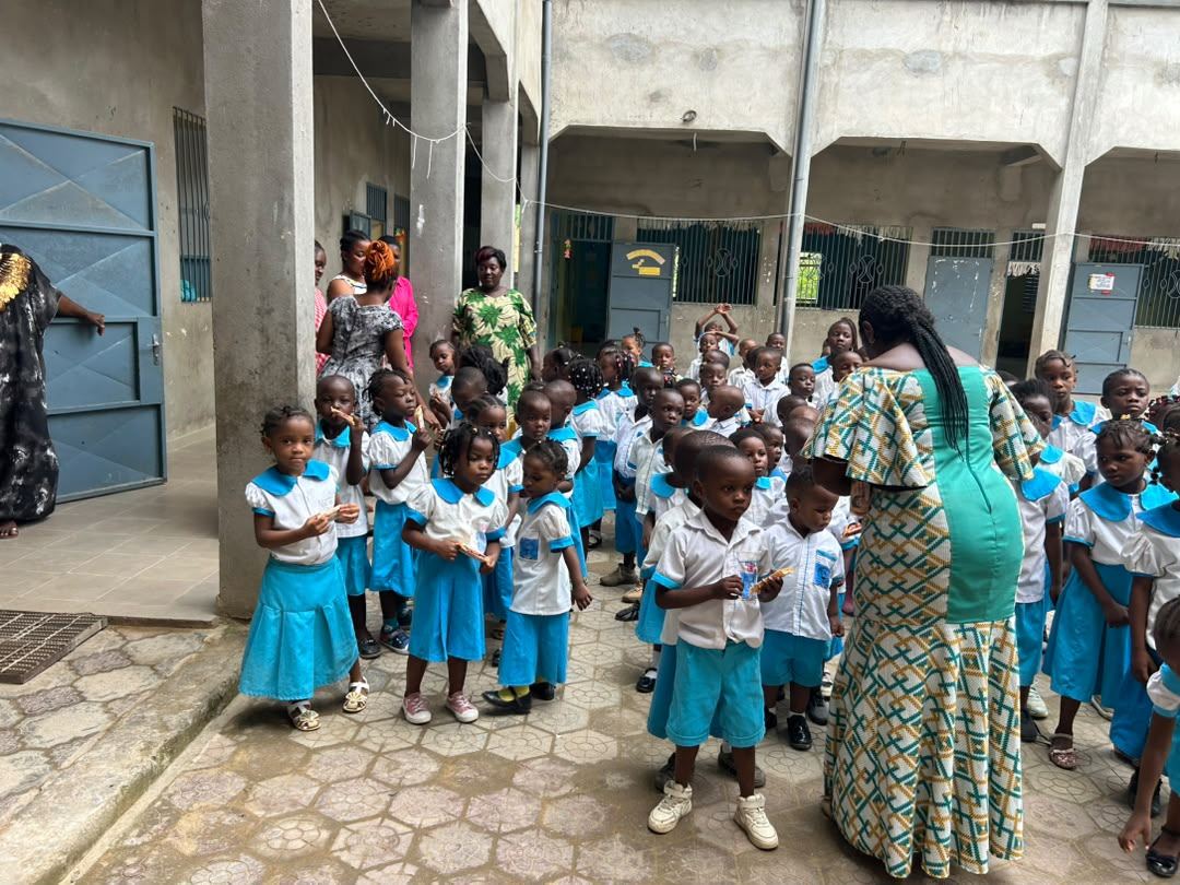 Élèves de maternelle rassemblés dans la cour avec leur enseignante.